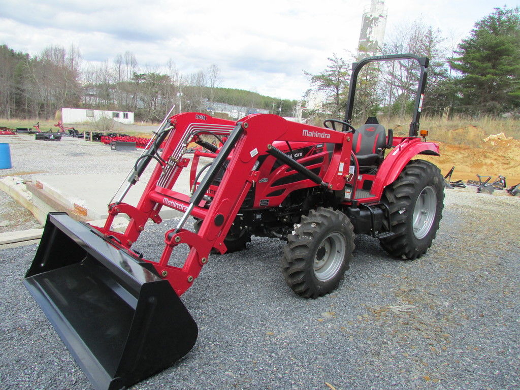 A red 2020 Mahindra 2600 Series 2655 HST OS tractor parked in a work-site on a cloudy day.